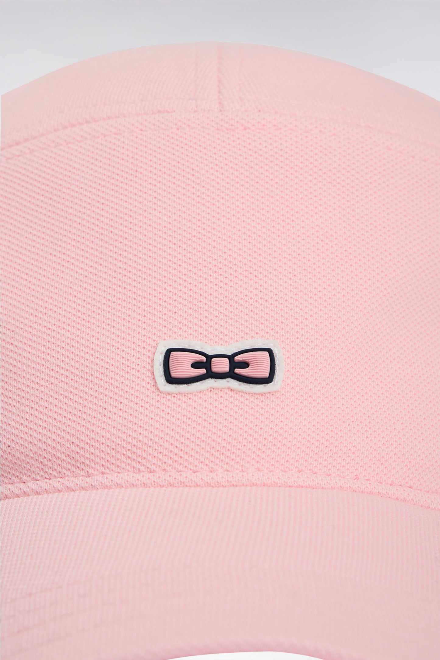 Pink cotton piqué cap with rubber bow tie badge